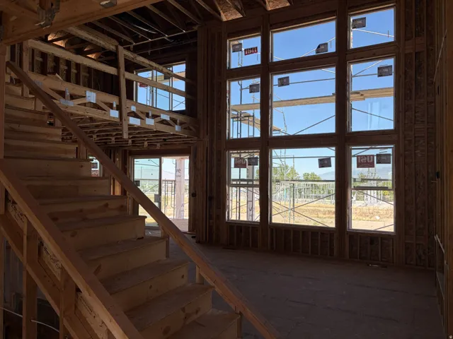 Two-story window wall, expansive windows, open-tread staircase, and exposed wood framing