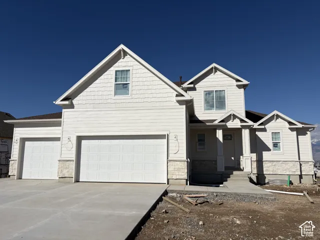 Multi-level exterior featuring light-toned horizontal siding, shake shingle gables, stone veneer base, and a three-car garage