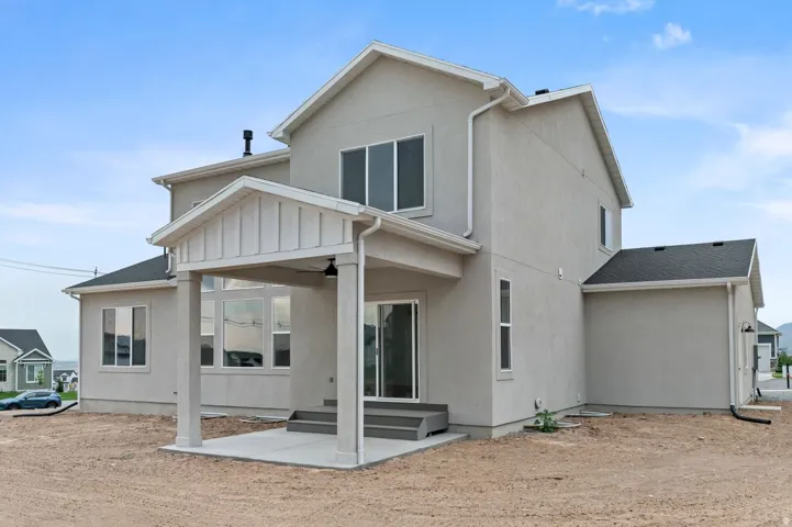 Stucco exterior with a covered patio, featuring a concrete pad and steps