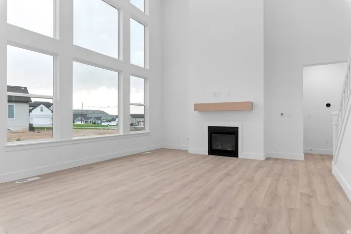 Soaring ceilings with extensive window fenestration, wood-finish flooring, a built-in fireplace, and a wood mantel