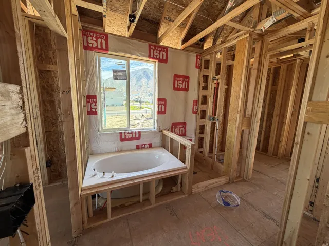 Built-in corner bathtub with a framed window overlooking a mountain backdrop
