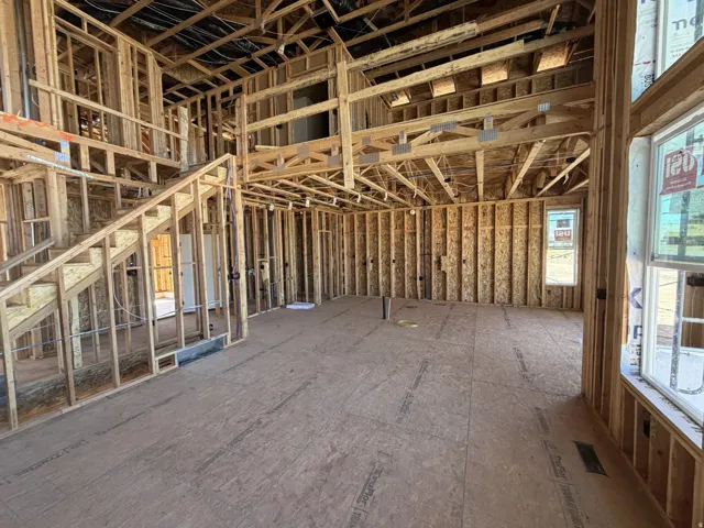 Expansive open-concept space featuring a staircase, upper-level balcony, and multiple windows allowing for abundant natural light