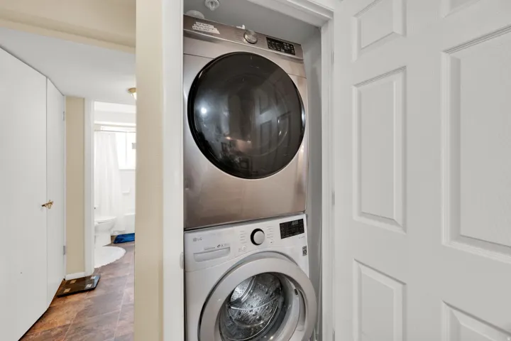 Stacked washer and dryer unit, white paneled door, and recessed lighting