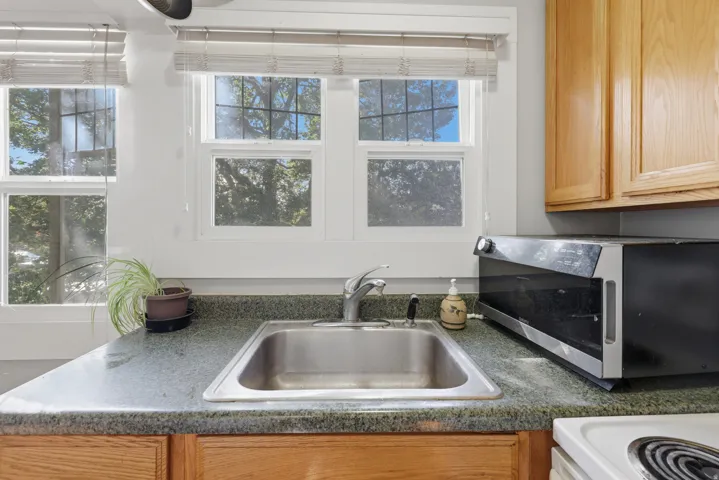 Stainless steel sink with a chrome faucet, speckled countertop, and wood-finish cabinetry