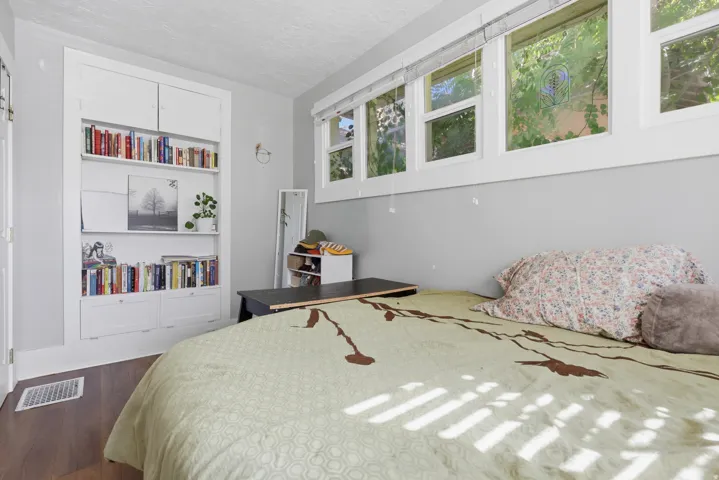 Built-in white shelving unit with lower cabinetry, wood-finish flooring, and multiple transom windows