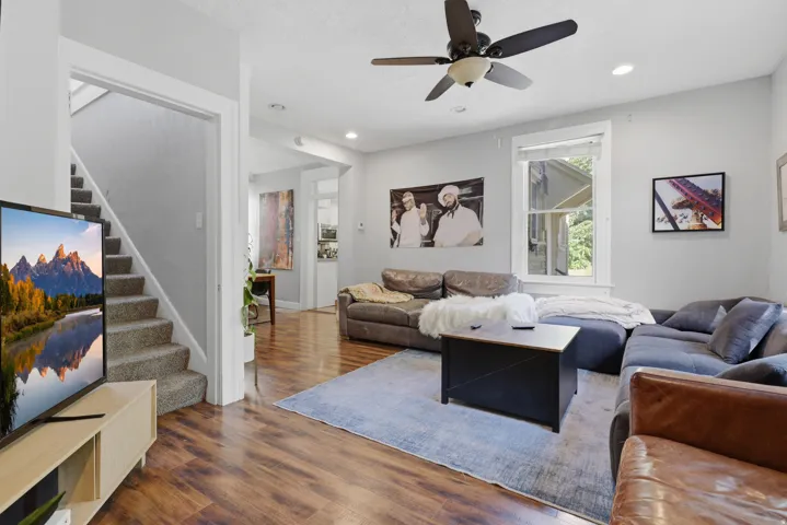 Wood-finish flooring, recessed lighting, ceiling fan, and carpeted staircase