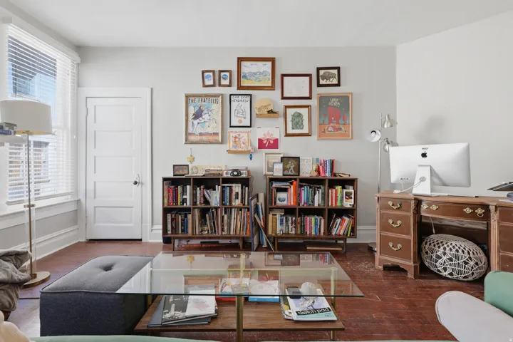 Hardwood flooring, painted paneled door, built-in shelving, white trim, and a window with blinds