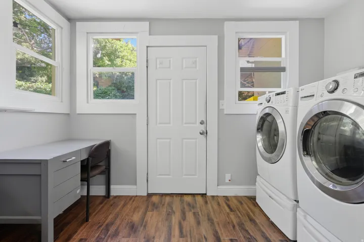 Wood-finish flooring, white paneled door, multiple windows, and a built-in desk with storage drawers