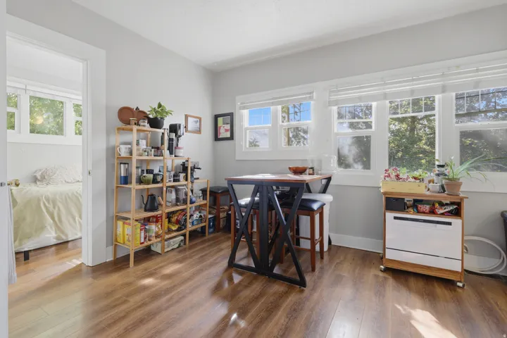 Wood-finish flooring throughout, multiple windows with white trim, and light gray wall paint