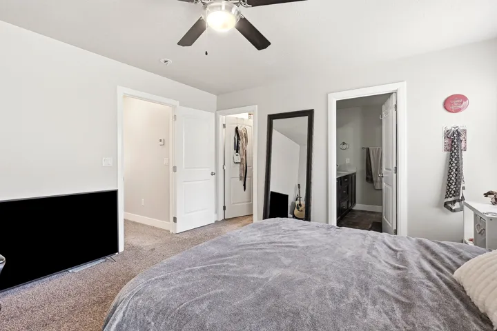 Plush carpeting, a ceiling fan with integrated lighting, and multiple doors leading to additional spaces