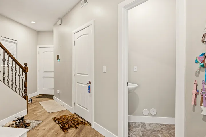 Wood-finish flooring with a staircase featuring a wood handrail and decorative metal balusters