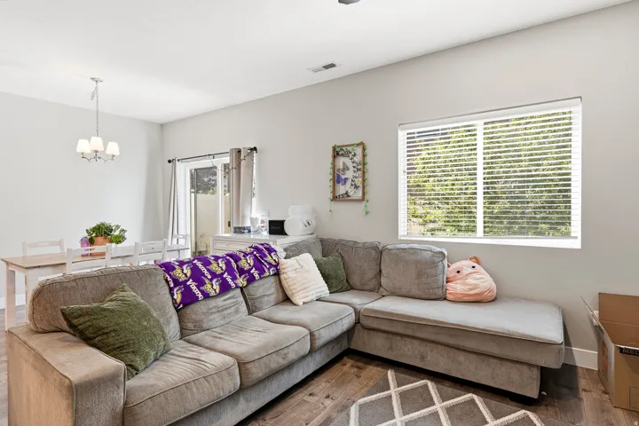 Light gray wall paint, wood-finish flooring, recessed ceiling lighting, white window blinds, and a white framed glass sliding door