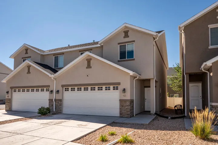 Two-story stucco exterior with stone accents, two attached garages, and individual entryways