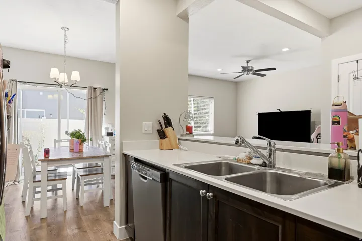 Kitchen featuring a double basin stainless steel sink, stainless steel dishwasher, and dark wood-finish cabinetry