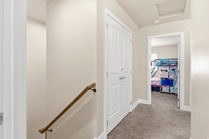 Hallway featuring carpeted flooring, a wooden handrail, and white paneled doors