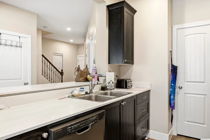 Kitchen featuring dark wood-finish cabinetry, light-toned countertops, and a stainless steel double sink