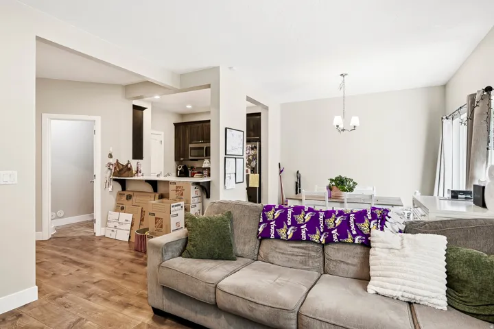 Open-concept living area with wood-finish flooring, a kitchen pass-through with a breakfast bar, and recessed lighting