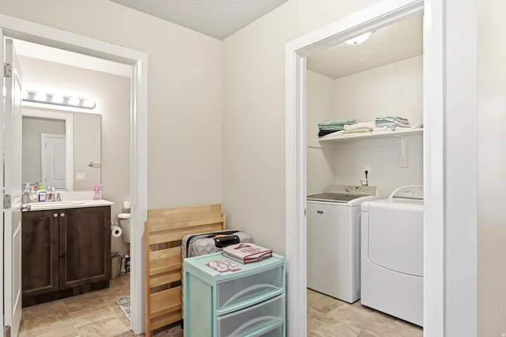 Laundry closet with built-in shelving, tile flooring, and overhead lighting