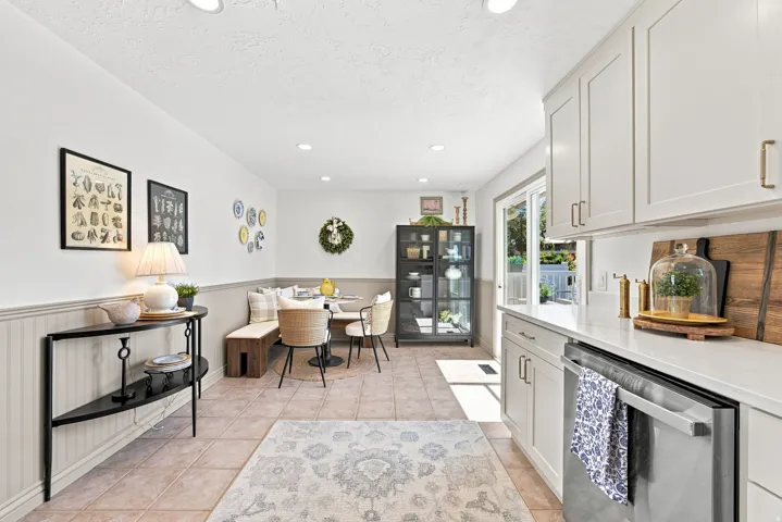 White shaker cabinetry, light-toned tile flooring, recessed lighting, beadboard wainscoting, and a sliding glass door