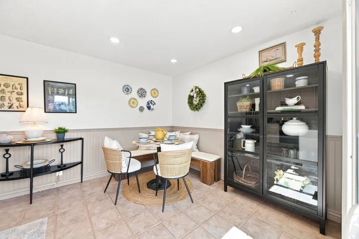 Recessed ceiling lighting, tiled flooring, wainscoting, built-in bench seating, and a display cabinet with glass doors