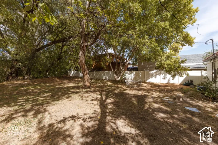 Expansive outdoor area featuring mature trees and a privacy fence