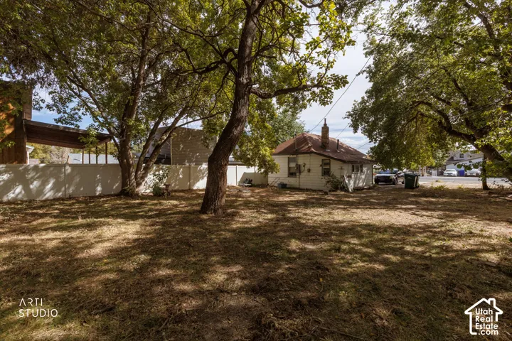 Expansive yard featuring mature trees and a perimeter fence