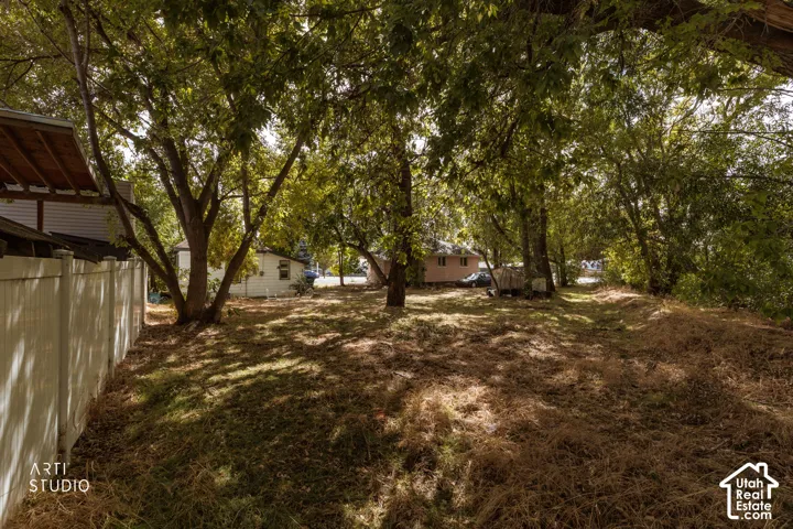 Expansive lot with mature trees and a white privacy fence