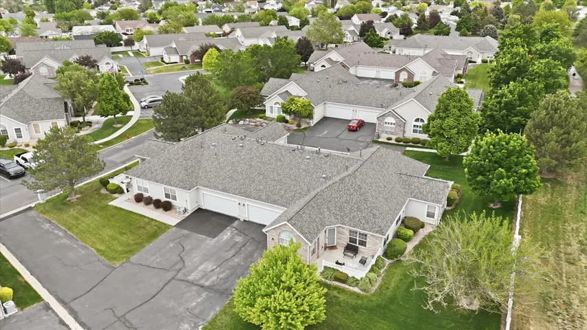 Paved driveways, attached garages, stone accents, mature landscaping, and an outdoor patio
