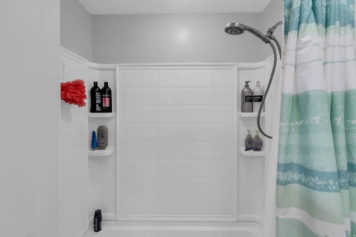 White shower-tub combination featuring integrated shelving and a handheld showerhead