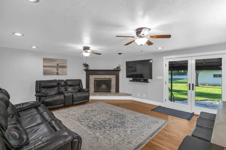 Wood-finish flooring with a corner fireplace featuring a stone hearth and wood mantel