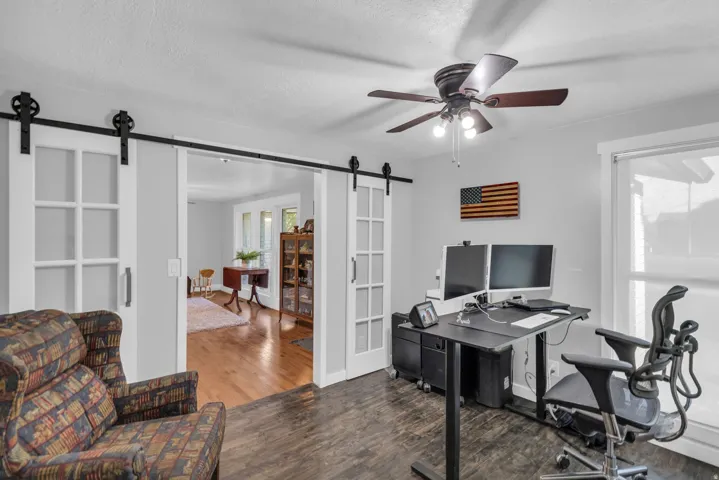 Room featuring dark wood-finish flooring, white walls, and a ceiling fan with integrated lighting
