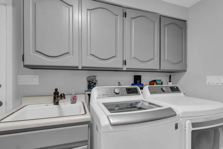 Upper cabinetry with decorative paneling, utility sink with bronze-finish faucet, and light gray wall paint