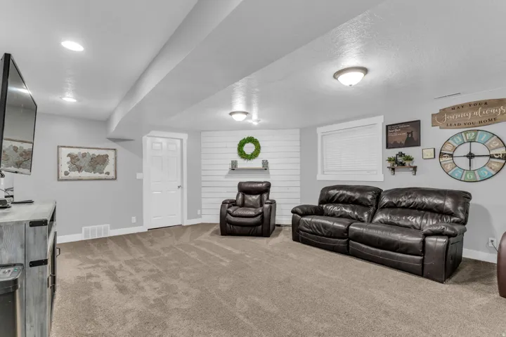 Recessed lighting, neutral wall tones, shiplap accent wall, durable carpeting, and white trim throughout