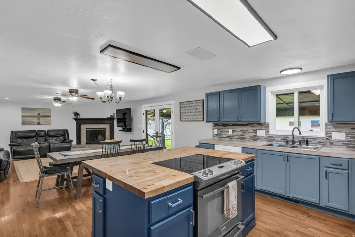 Kitchen with blue cabinetry, butcher block island countertop, stainless steel appliances, and tile backsplash