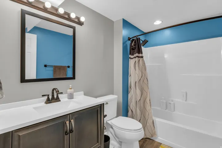 White vanity countertop with an integrated sink, dark wood-finish cabinetry, and a framed mirror
