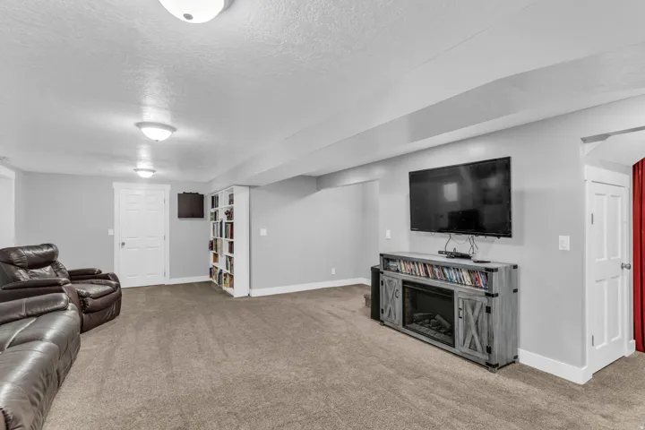 Carpeted flooring, recessed lighting, built-in shelving, and a wall-mounted entertainment console with an integrated electric fireplace