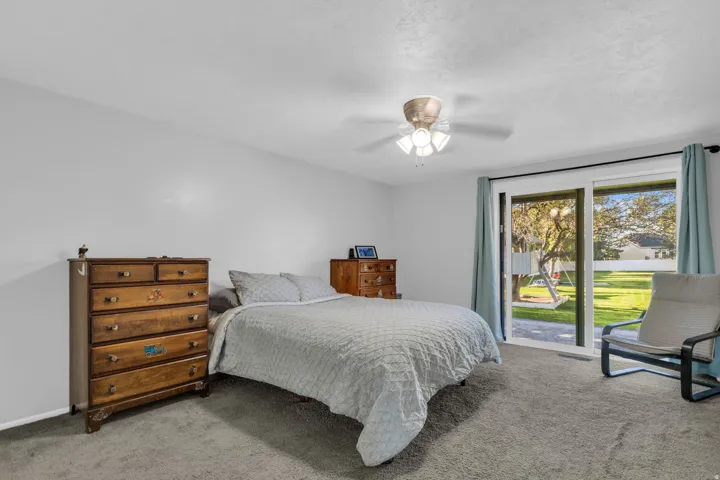 Sliding glass door leading to exterior, ceiling fan with integrated lighting, and carpeted flooring