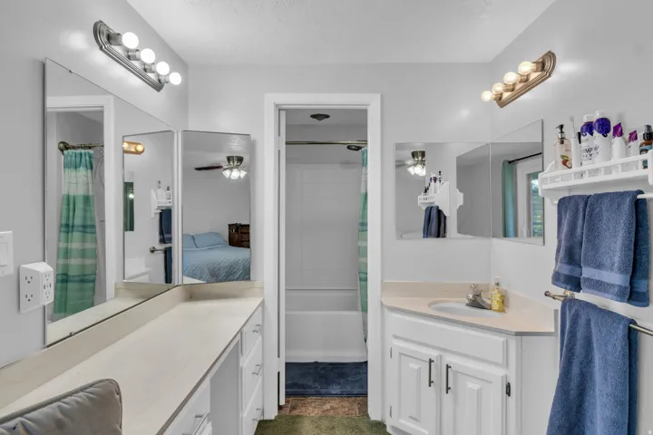 Dual vanity areas with integrated cabinetry, an undermount sink, and a built-in bathtub with shower