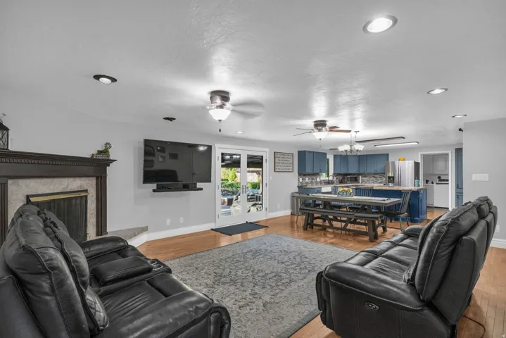 Open concept living area with wood-finish flooring, recessed lighting, and a fireplace with a wood mantle