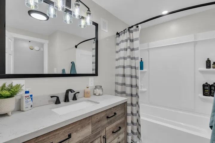 Wood-finish vanity with an integrated rectangular sink, stone-finish countertop, and matte black fixtures