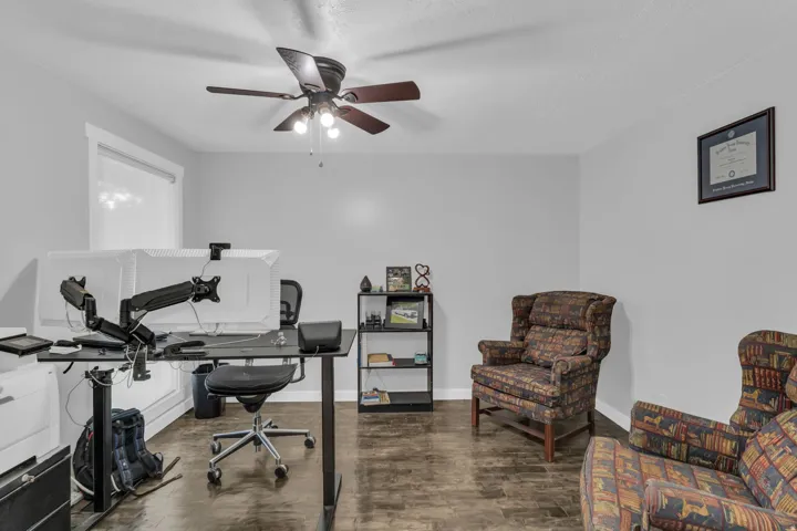 Wood-finish flooring, light gray walls, white trim, and a ceiling fan with integrated lighting
