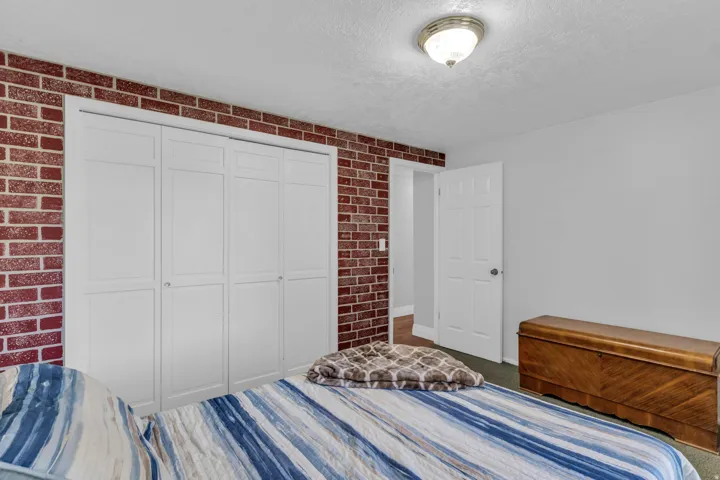Textured brick accent wall, white bi-fold closet doors, ceiling-mounted light fixture, white interior door