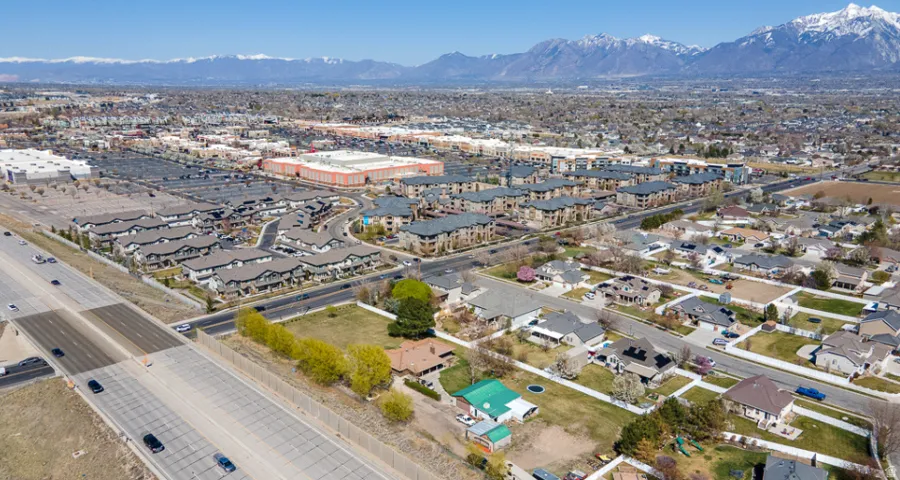 Expansive urban landscape with a prominent highway, diverse residential areas, commercial buildings, and a distant mountain range