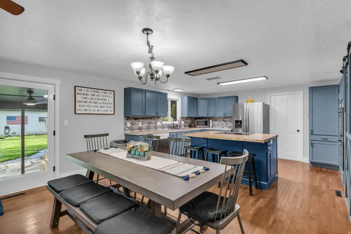 Kitchen featuring blue cabinetry, a central island with wood-finish countertop, stainless steel appliances, and a tiled backsplash