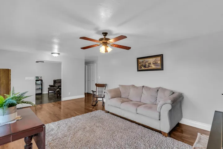 Wood-finish flooring, ceiling fan with light fixture, recessed lighting, white wall paint, and white trim