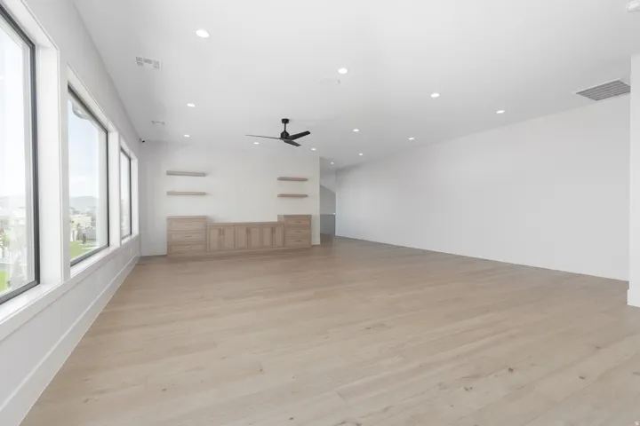 Expansive room with wood-finish flooring, recessed lighting, and a contemporary ceiling fan