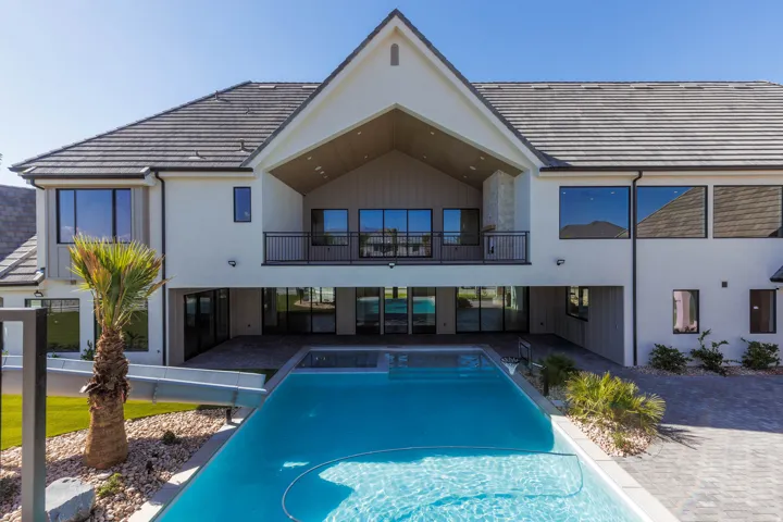 Expansive backyard featuring a built-in swimming pool, integrated slide, and a spacious covered patio