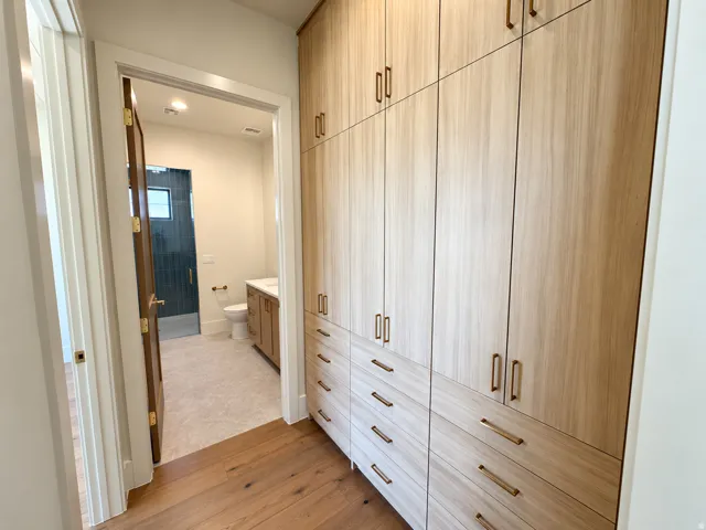 Integrated custom cabinetry featuring ample storage, warm wood-finish flooring, and bronze-toned hardware