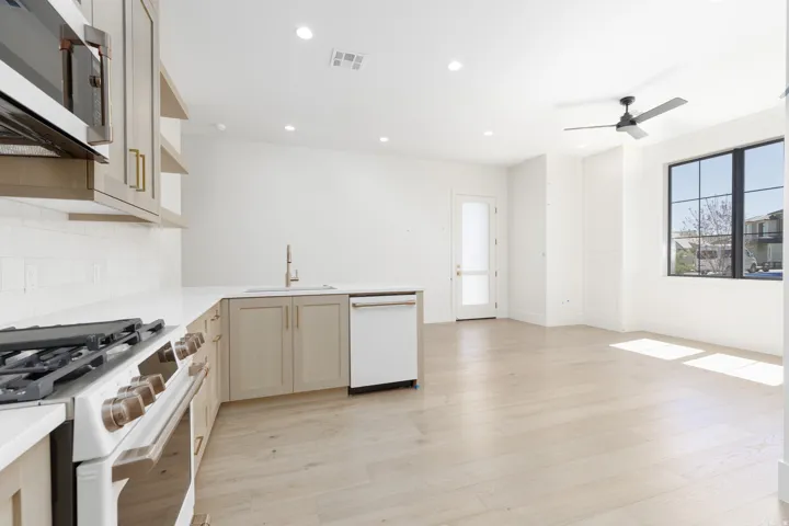 Gourmet kitchen with white subway tile backsplash, white countertops, stainless steel appliances, and light wood-finish cabinetry