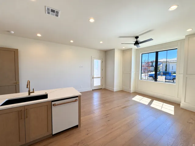Open-concept living space with wood-finish flooring, recessed lighting, and a contemporary ceiling fan